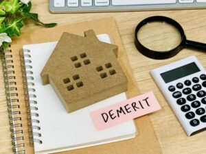 「DEMERIT」と書かれたメモ、電卓、住まいのオブジェ