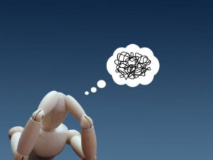 頭を抱える人形と複雑に絡まった思考の吹き出し