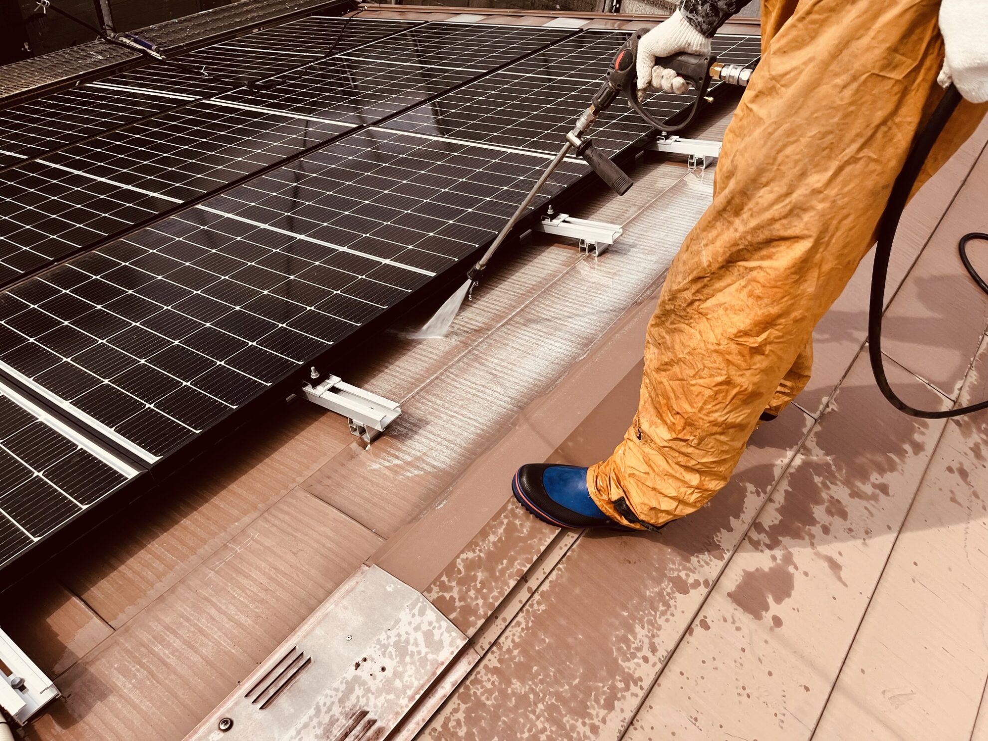 太陽光パネルの架台周辺を洗浄している屋根塗装前の作業